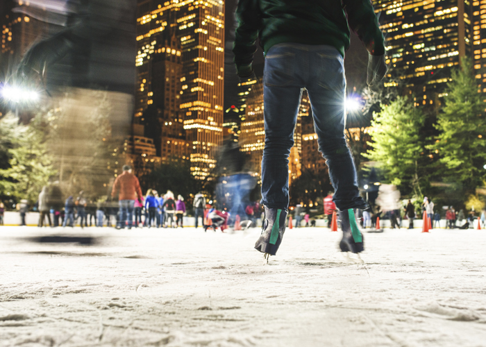 Ice skaters enjoy holiday skating at an urban outdoor seasonal ice rink.