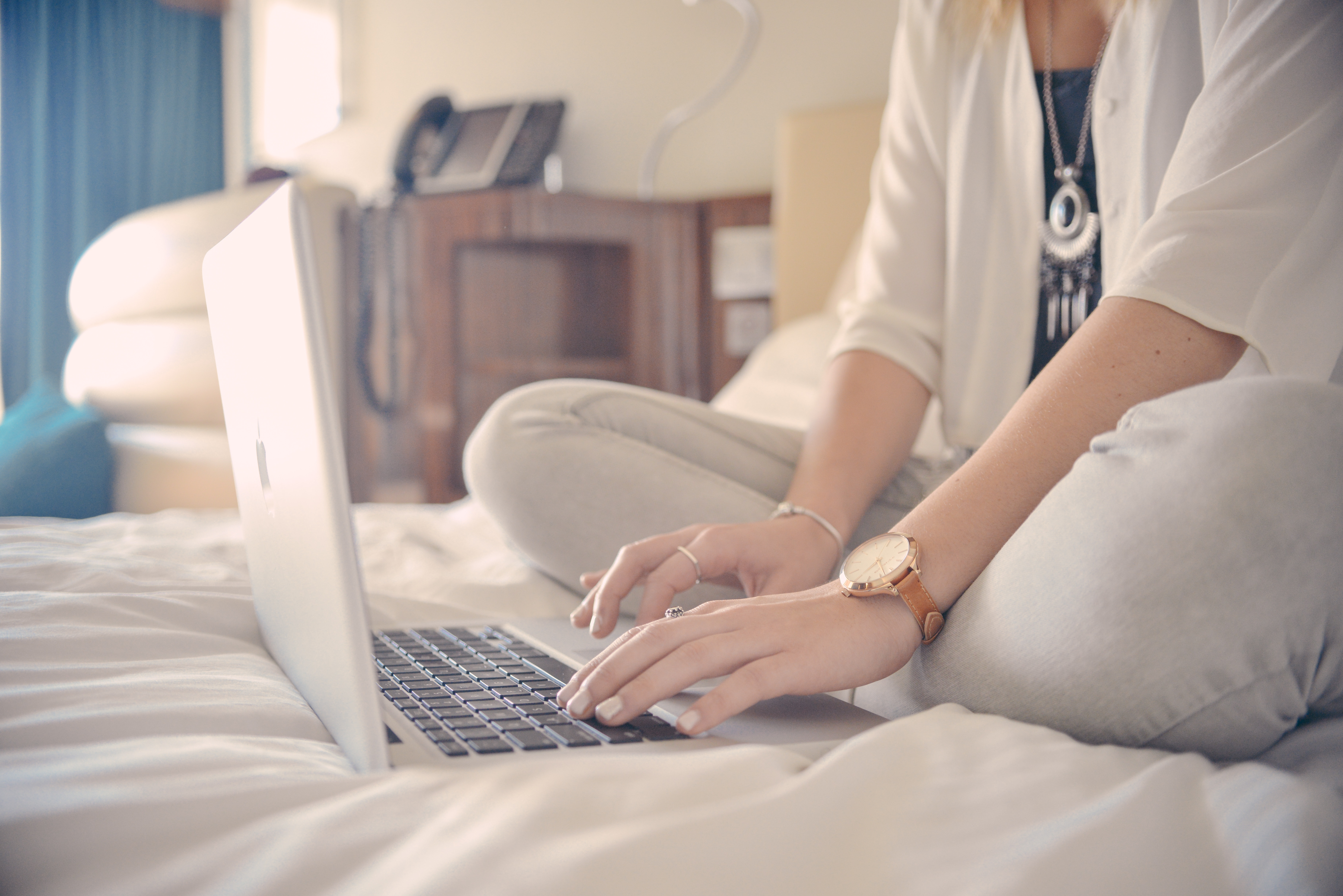 Woman working on a laptop on her bed.