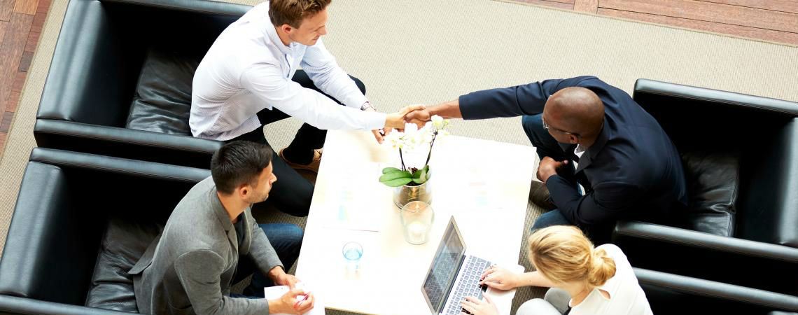 An aerial view of a four-person team of professionals collaborating in an informal meeting space.