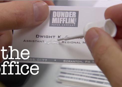 In a screeshot from The Office, Dwight uses white-out to alter his business cards.