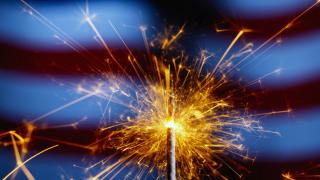 Celebrating the 4th of July with a sparkler against a backdrop of the American flag