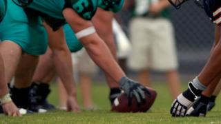 Football teams face off at the line of scrimmage, waiting for the snap.