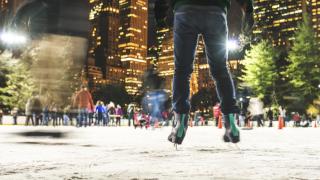 Ice skaters enjoy holiday skating at an urban outdoor seasonal ice rink.