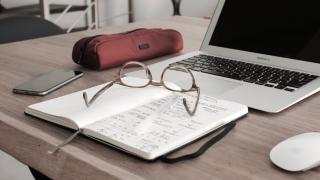 Glasses on notebook in front of laptop